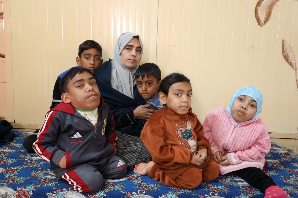 A mother seated on the ground, surrounded by her five children.