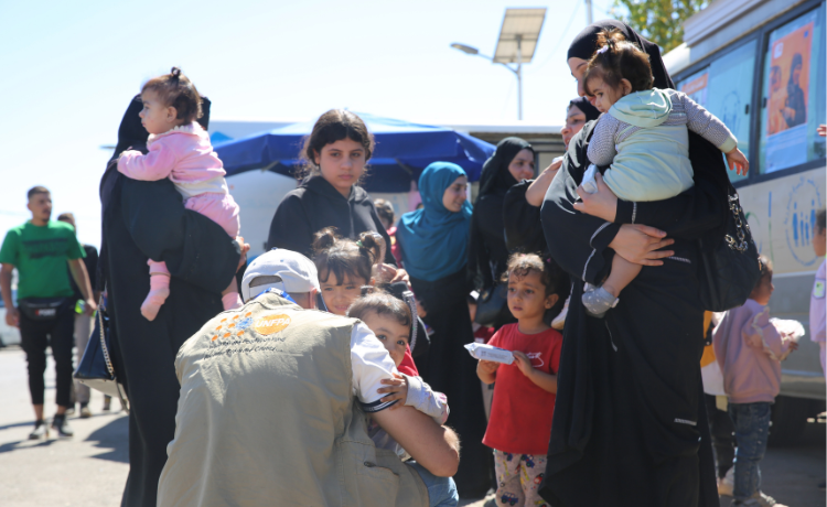 Samah (left) holes one of her three children at the border between Lebanon and Syria. © UNFPA Syria / Omaya Al Mekdad