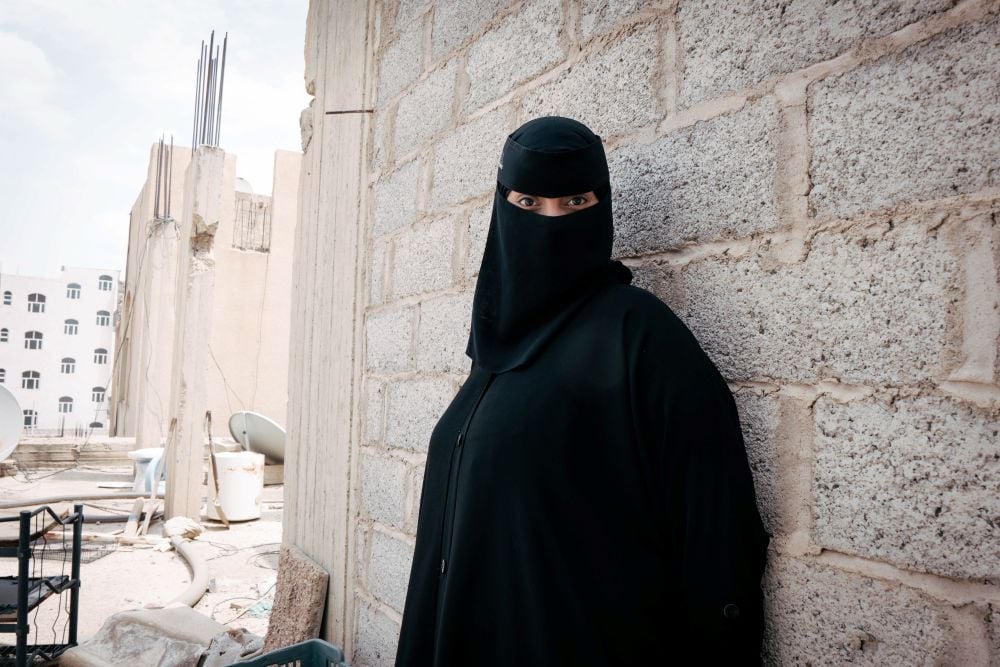 A Yemeni woman, clad in a traditional veil, stand tall.