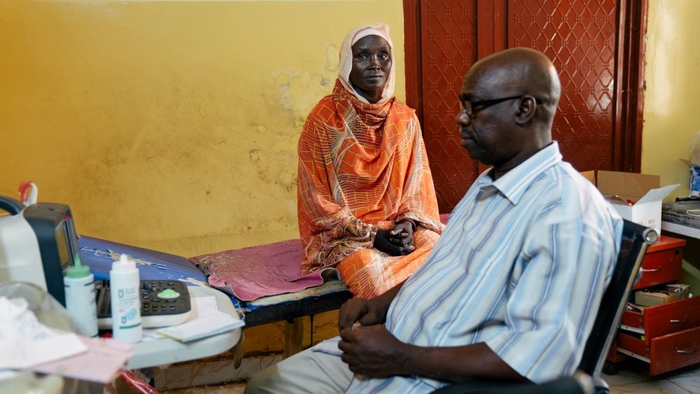 In a clinic, a woman who survived an obstetric fistula consults with her physician.