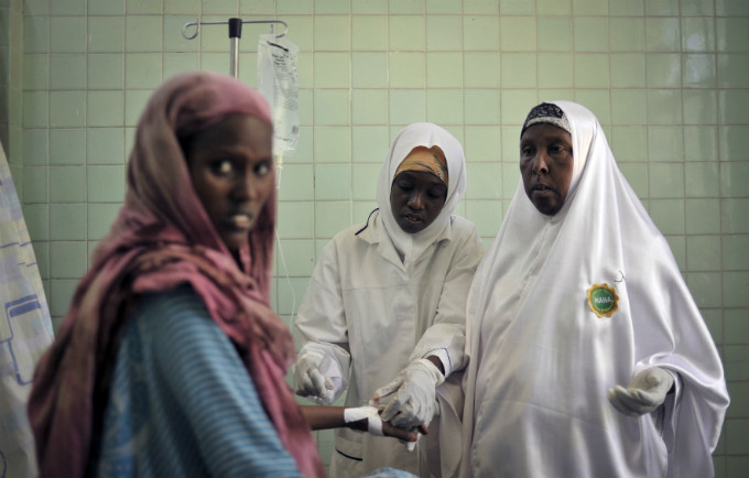 Two midwives place an intravenous drip for a patient at the maternity ward of Banadir Hospital in Mogadishu.
