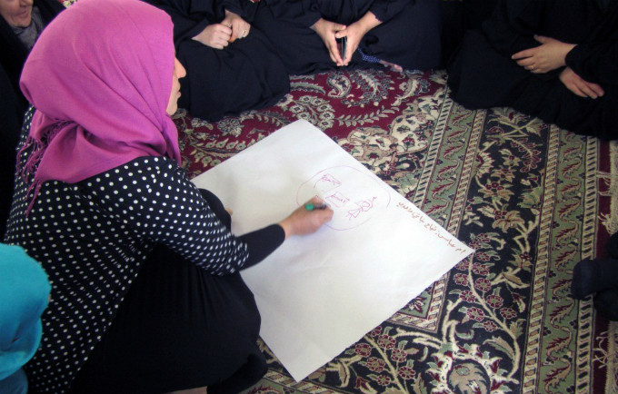 A displaced woman writes down her dreams as part of the "Our Dreams" group support session