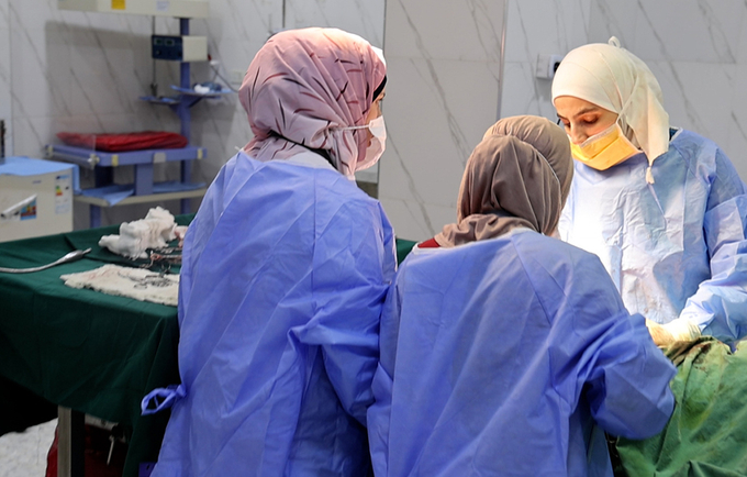  تجري ثلاث طبيبات توليد عملية جراحية في غرفة العمليات في مستشفى إدلب للولادة. ثلاثة عشر عاما من النزاع والنقص الحاد في التمويل ي