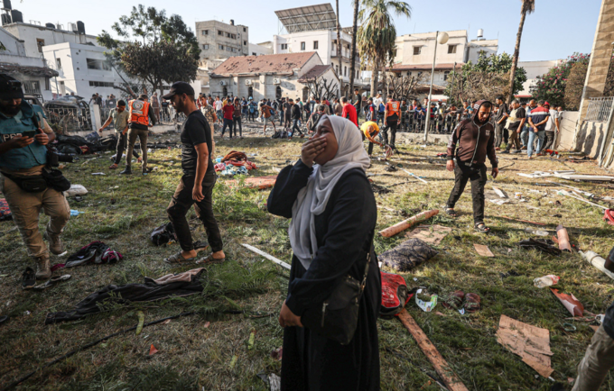 A Palestinian woman around the belongings of Palestinians cries at the garden of Al-Ahli Arabi Baptist Hospital after it was hit