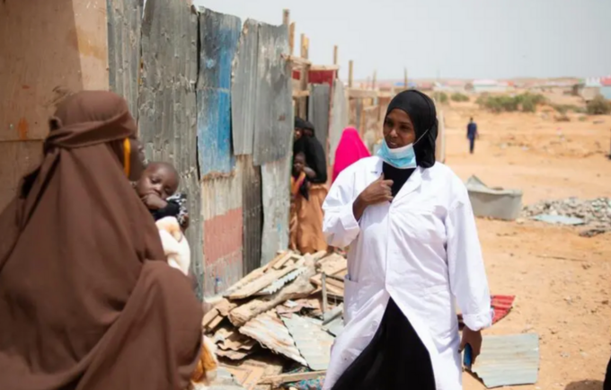 A nurse walks through an settlement camp for displaced people in Garowe, Puntland, speaking to women as part of an initiative to