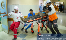 Injured man lying on a stretcher being rushed into a hospital room. © WHO