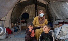   Um Abdul Hamid sits with her children in front of their tent in Al-Hamam makeshift camp in Jinderis