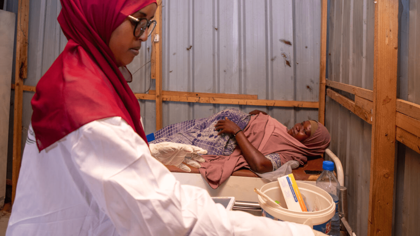 A midwife prepares and a pregnant woman lying on a bed