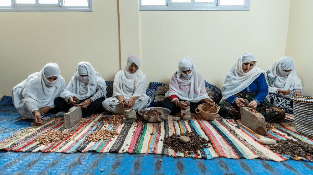 A group of women hitting argan nuts on stone anvils with rocks to get to the kernels. Photo © UNFPA Morocco