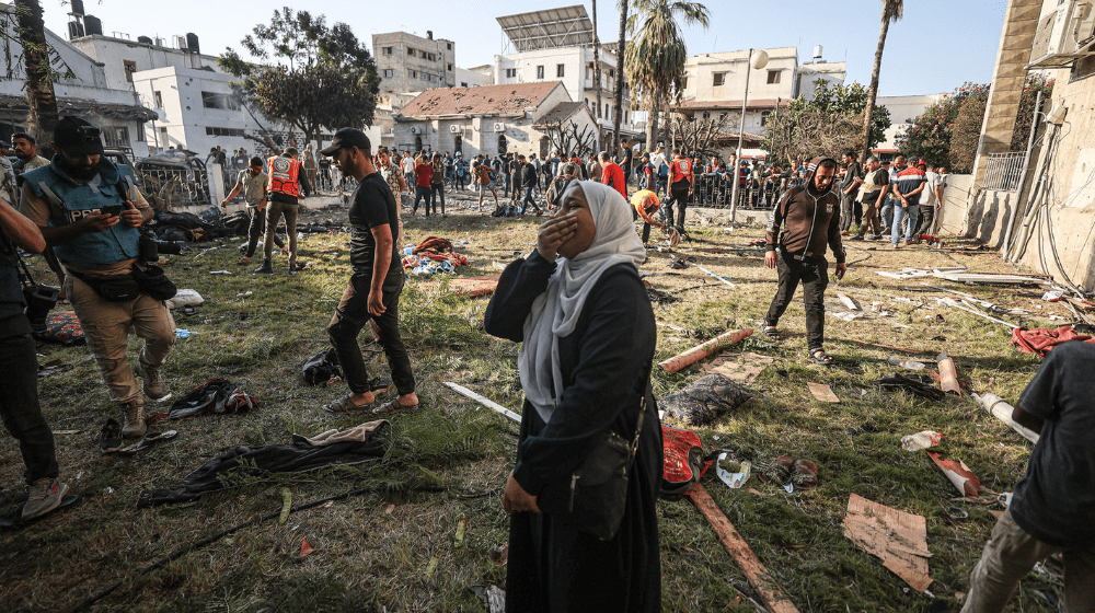 A Palestinian woman around the belongings of Palestinians cries at the garden of Al-Ahli Arabi Baptist Hospital after it was hit