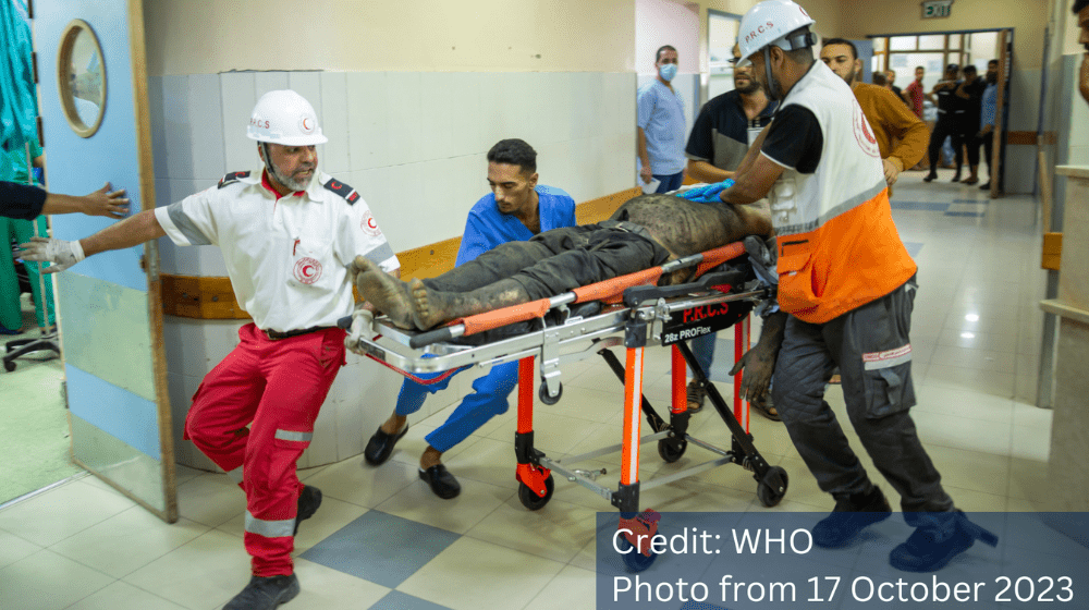 Injured man lying on a stretcher being rushed into a hospital room. © WHO