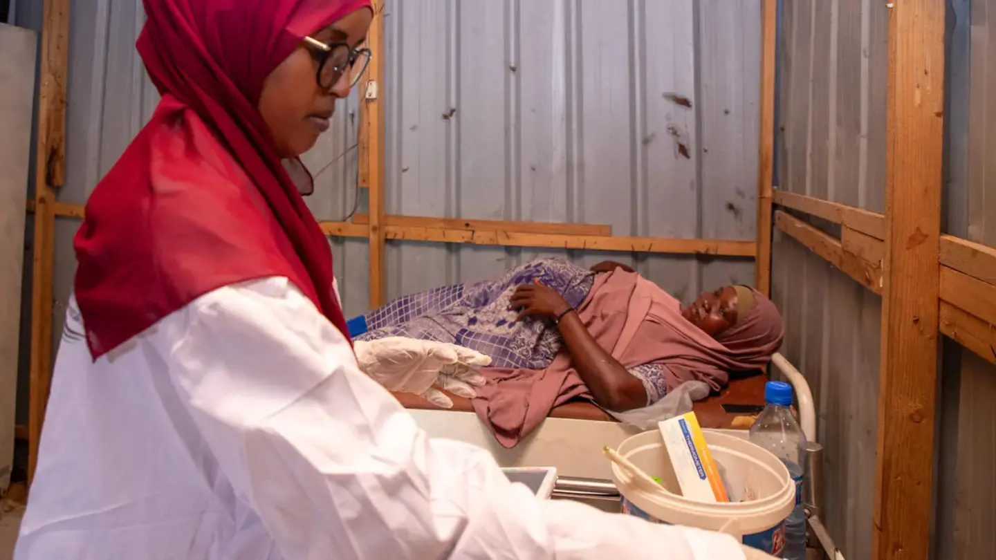 A midwife prepares and a pregnant woman lying on a bed