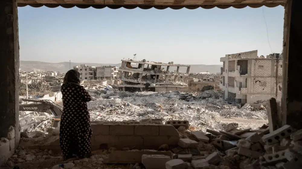 A woman looks over a scene of destruction following the earthquakes, Jinderis, Syria.  © UNFPA/Karam Al-Masri