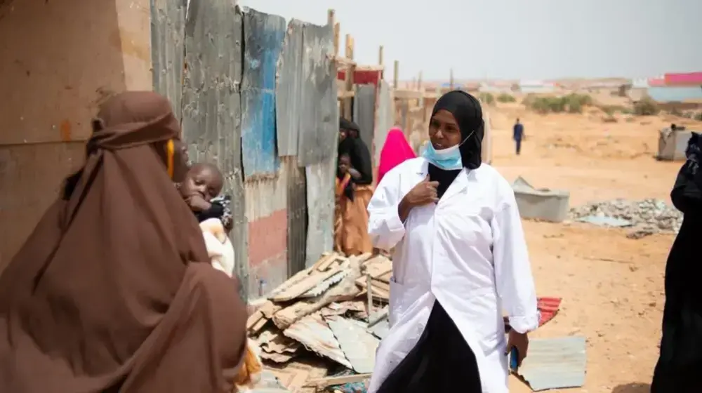 A nurse walks through an settlement camp for displaced people in Garowe, Puntland, speaking to women as part of an initiative to