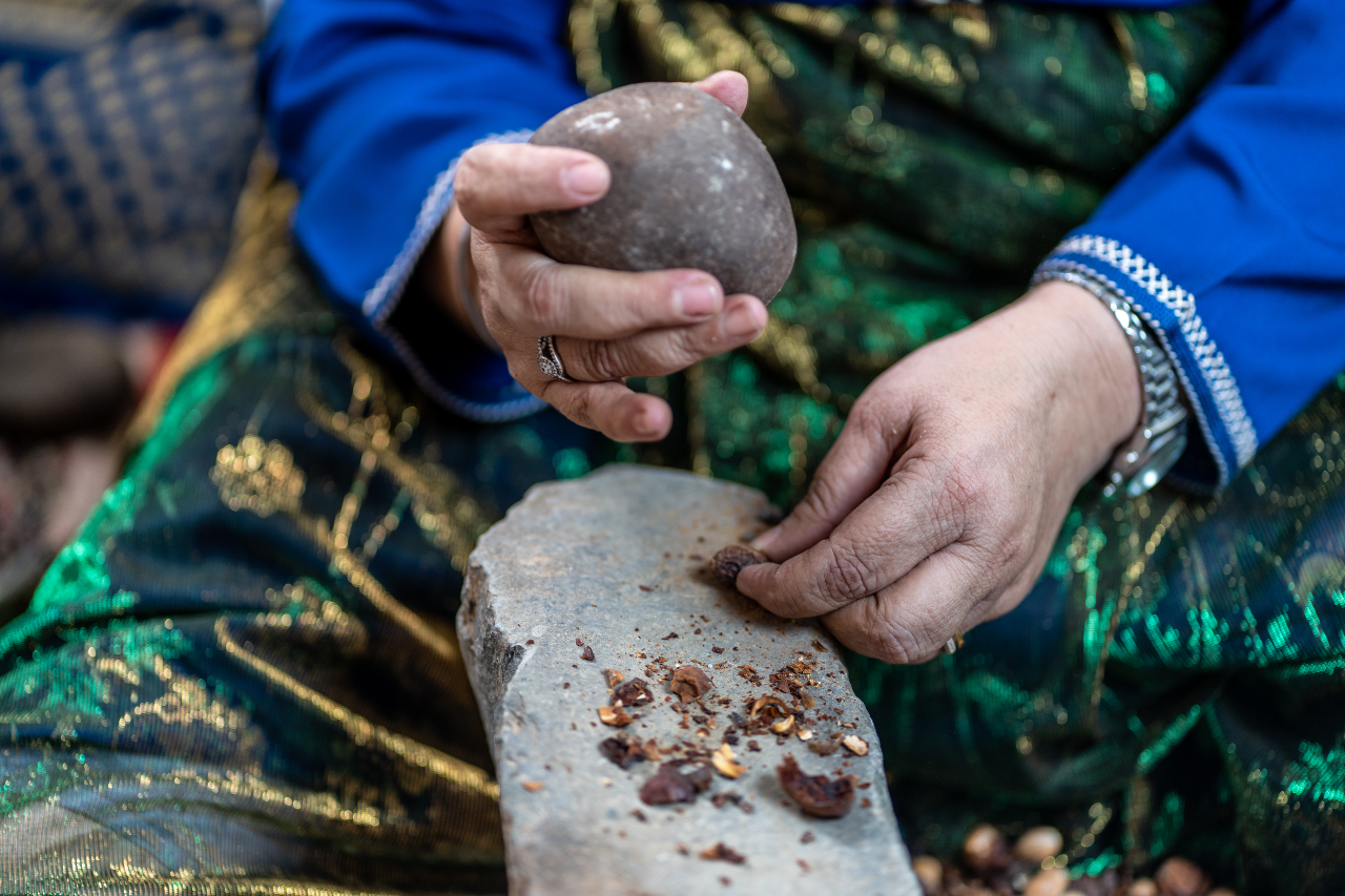 فادما تضرب حبات الأركان على سندان حجري بحجر للحصول على  اللوز. الصورة © صندوق الأمم المتحدة للسكان، المغرب